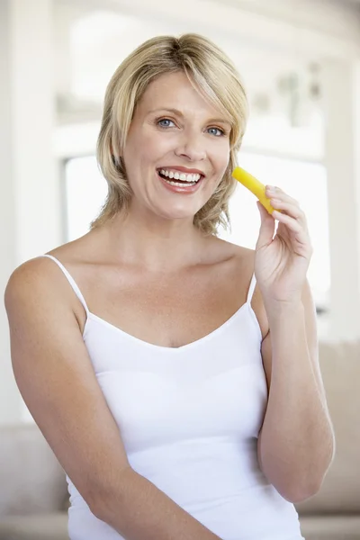 Mujer adulta sonriendo en la cámara y comiendo piña —  Fotos de Stock