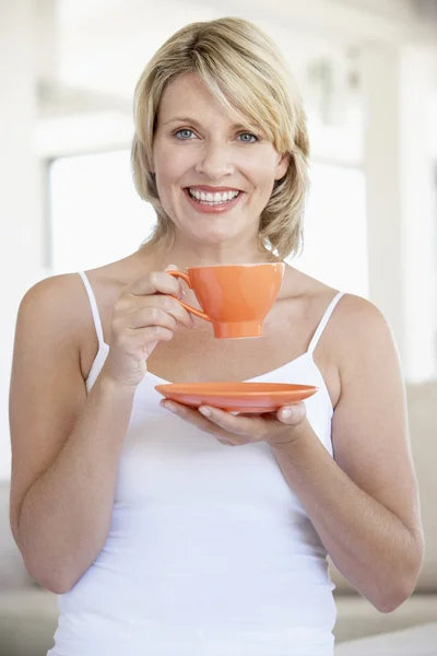 Mujer adulta media sosteniendo la taza de té y sonriendo en la cámara —  Fotos de Stock