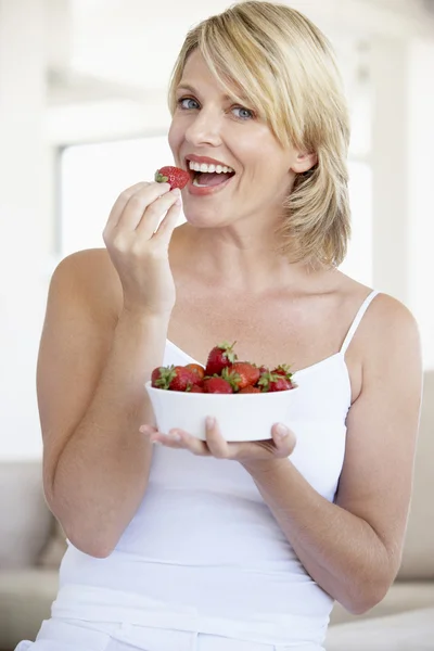 Femme adulte moyenne mangeant un bol de fraises — Photo