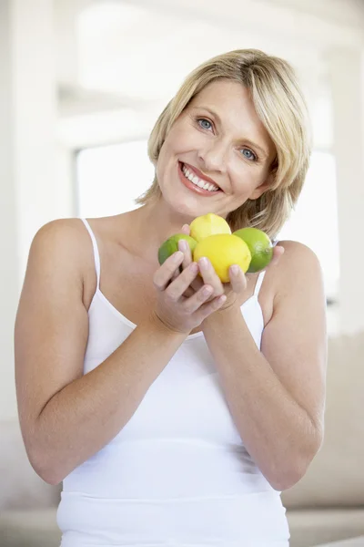 Mulher adulta média segurando frutas frescas e sorrindo para a câmera — Fotografia de Stock