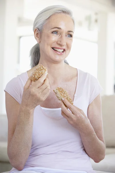 Äldre kvinna äta mörkt bröd rulle — Stockfoto
