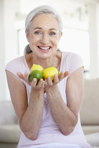 Senior vrouw holding vruchten en glimlachen naar de camera — Stockfoto
