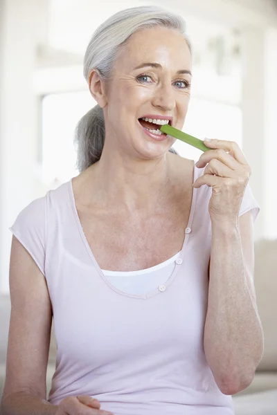 Mujer mayor comiendo un palo de apio — Foto de Stock