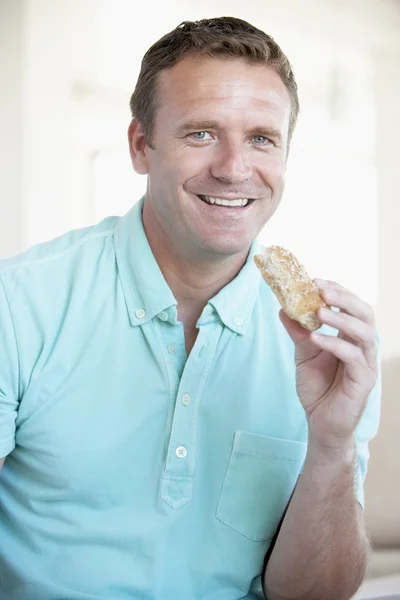 Homem adulto médio comendo pão marrom rolo — Fotografia de Stock