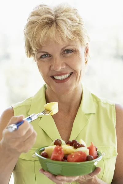 Mulher de meia-idade comendo salada de frutas frescas — Fotografia de Stock