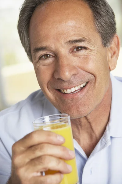 Średnim wieku człowiek picie świeżego soku pomarańczowego — Zdjęcie stockowe