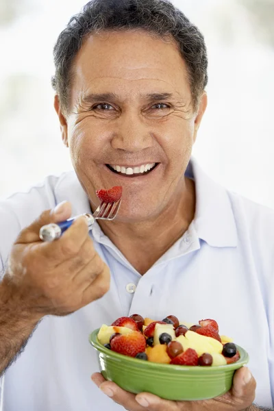 Senior man eten van verse fruitsalade — Stockfoto