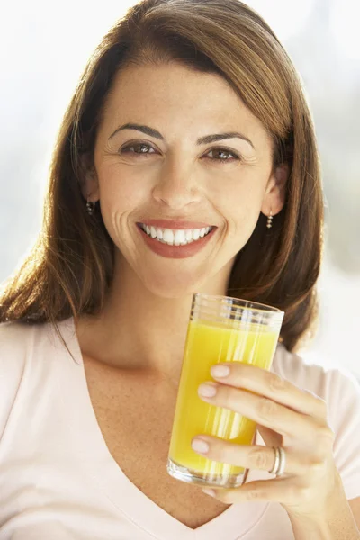 オレンジ ジュースのガラスを保持している大人の女性を笑顔で半ば、 — ストック写真