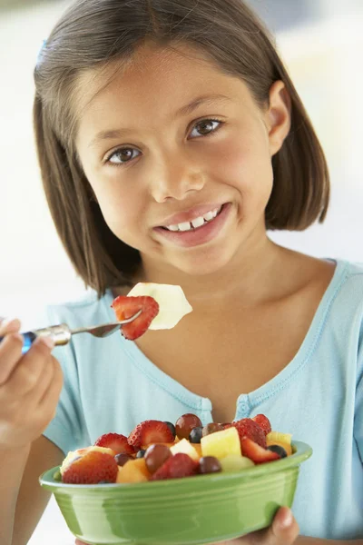 Menina comendo uma tigela de salada de frutas frescas — Fotografia de Stock