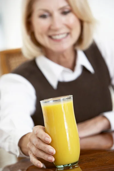 年配の女性の新鮮なオレンジ ジュースのガラスを飲む — ストック写真