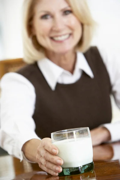 年配の女性 牛乳のガラスを保持しているカメラに微笑んでいますー — ストック写真