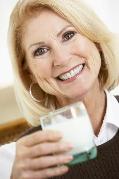 Donna anziana che tiene un bicchiere di latte, sorridente alla macchina fotografica — Foto Stock
