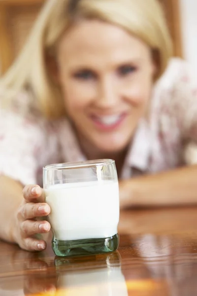 代の女性 牛乳のガラスを保持しているカメラに微笑んでいますー — ストック写真