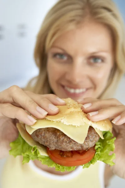 中旬成年女性持有一个汉堡包 在对照相机微笑 — 图库照片