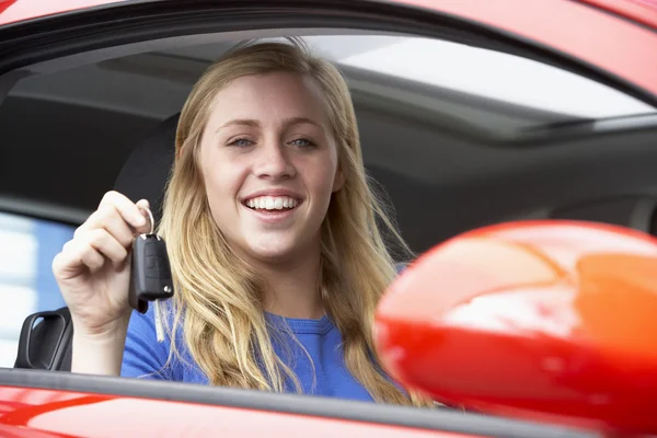 Arabanın içinde otururken, arabanın anahtarları tutan ve gülümseyen genç kız — Stok fotoğraf