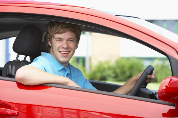 Menino adolescente sentado no carro, sorrindo para a câmera — Fotografia de Stock