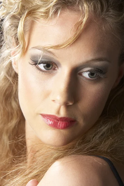 Mujer joven usando maquillaje, luciendo reflexivo — Foto de Stock