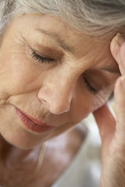 Äldre kvinna med huvudet i händerna ser trött — Stockfoto