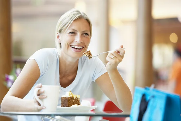 Kvinna äta en bit av kakan på köpcentret — Stockfoto