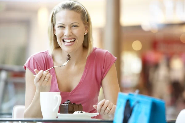 Mujer comiendo un pedazo de pastel en el centro comercial —  Fotos de Stock