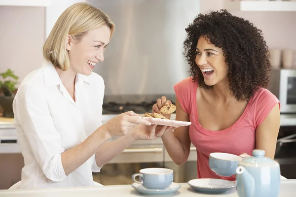 Kvinnliga vänner njuta av te och kakor hemma — Stockfoto
