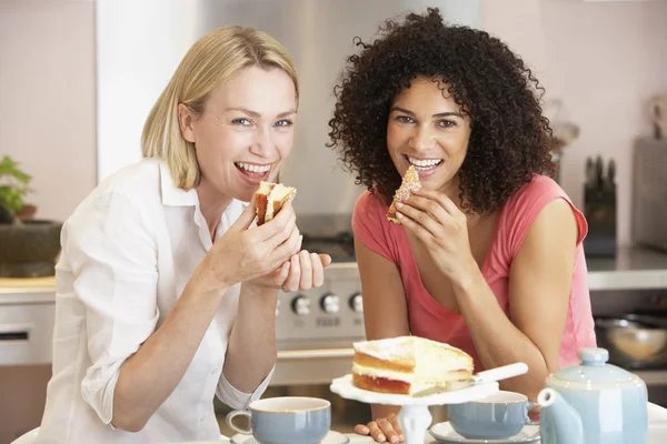 Amigos do sexo feminino desfrutando de chá e bolo em casa — Fotografia de Stock