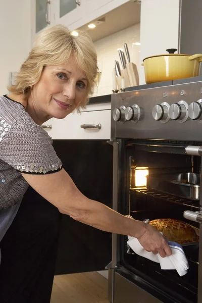 Женщина вынимает еду из духовки — стоковое фото