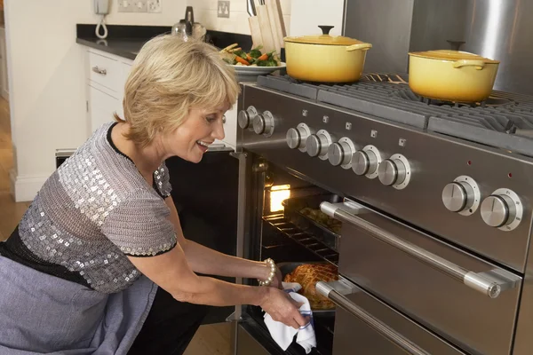 Mujer sacando comida del horno — Foto de Stock