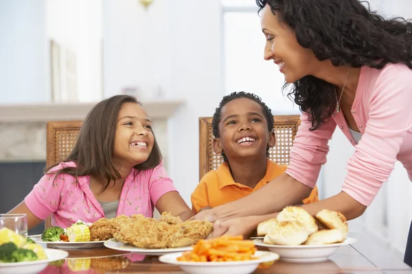 Moeder een maaltijd serveren aan haar kinderen thuis — Stockfoto