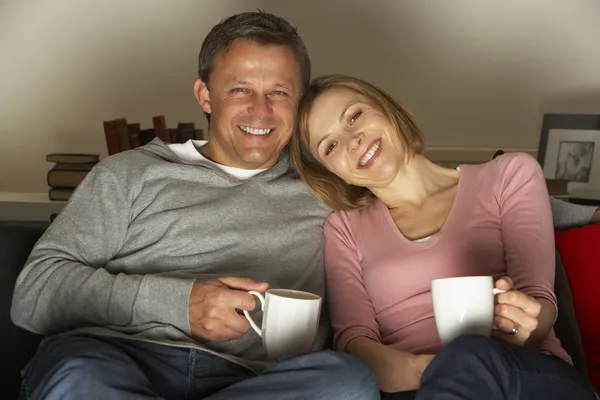 Casal com canecas de café assistindo televisão — Fotografia de Stock