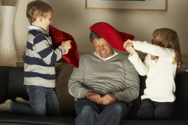 Отец и двое детей в борьбе подушками — стоковое фото