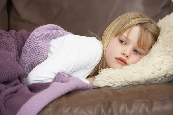 年轻女孩不舒服躺在沙发上 — 图库照片