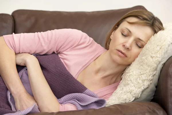 Женщина нездорова и лежит на диване — стоковое фото
