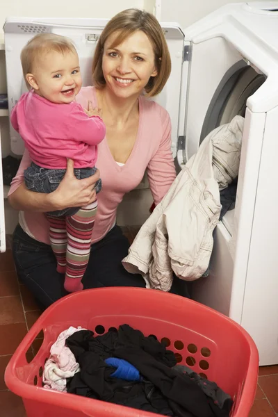 Mulher Fazendo Lavanderia Segurando Filha Bebê — Fotografia de Stock