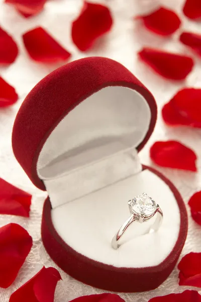 Diamantring i hjärtat formade box omgiven av rosenblad — Stockfoto