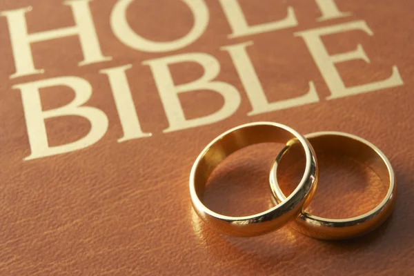 Anéis de casamento descansando em uma Bíblia Sagrada — Fotografia de Stock