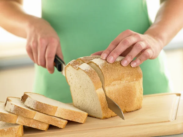 Женщина Нарезающая Буханку Белого Хлеба — стоковое фото