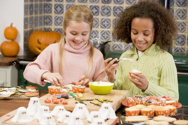 Two young girl friends at Halloween making treats and smiling Stock Image