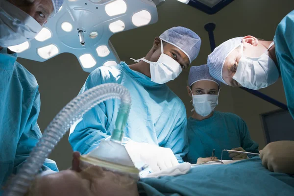 Drei Chirurgen operieren einen Patienten Stockbild
