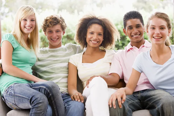 Grupp tonåringar som sitter på en soffa Stockbild