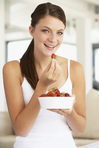 年轻女子吃一碗新鲜草莓 免版税图库照片