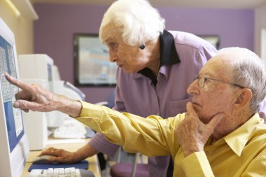 Senior woman helping senior man use computer clipart