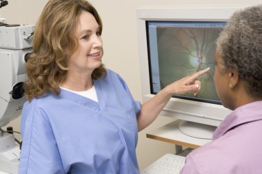 Nurse Explaining Eye Exam Results To Patient clipart