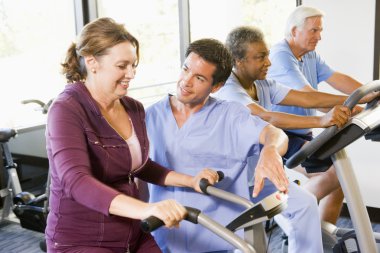 Nurse With Patient In Rehabilitation Using Exercise Machine clipart