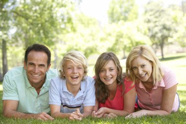 Couple And Their Teenage Children Lying On Grass clipart