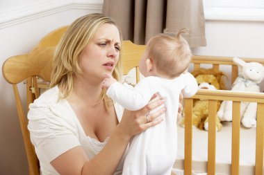 Stressed Mother Holding Baby In Nursery clipart