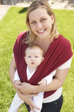 Baby In Sling With Mother Outdoors clipart