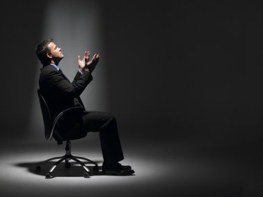 Businessman Sitting In Spotlight clipart