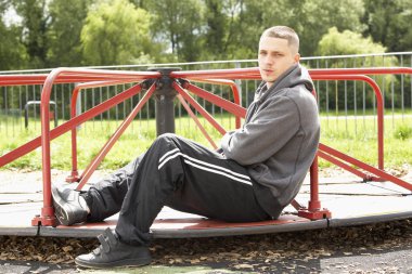 Young Man Sitting In Playground clipart