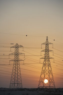 Electricity Pylons Silhouetted At Sunset clipart